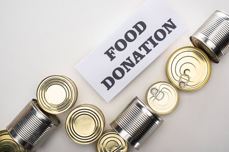 top view of cans with canned food on white background with food donation cardの写真素材