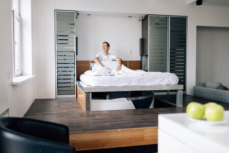 selective focus of man looking at window in bedroomの写真素材