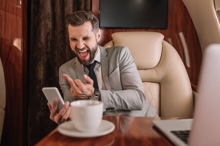 aggressive businessman showing muddle finger while having video chat on smartphone
