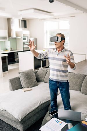 surprised man in virtual reality headset gesturing at home
