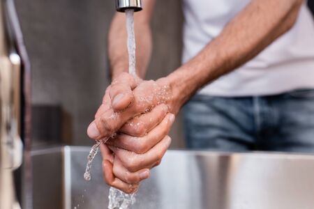 Selective focus of man washing hands at homeの写真素材