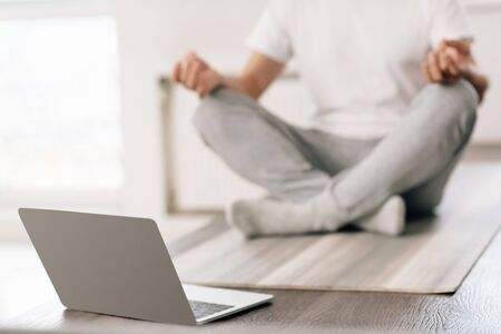 selective focus of laptop near man sitting in lotus pose at homeの写真素材