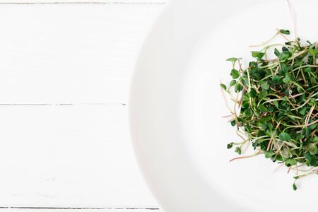 top view of fresh microgreen on plate on white wooden surfaceの写真素材