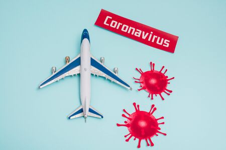 Top view of toy near card with coronavirus lettering and decorative coronavirus molecules on blue