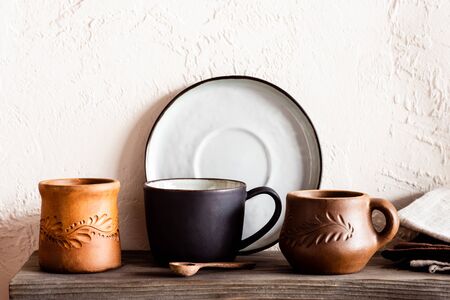 wooden spoon near clay cups and plate in kitchen