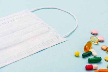 High angle view of medical mask near colorful pills on blue backgroundの写真素材