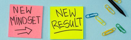 Top view of sticky notes with new mindset and new result lettering with paper clips and pencil on...