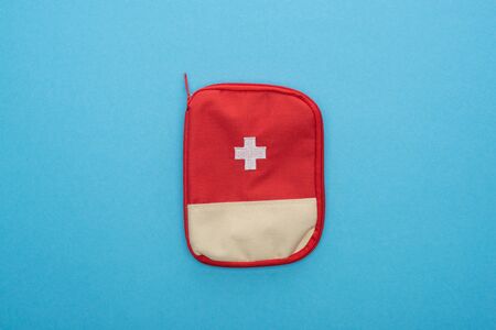 top view of red first aid kit on blue background