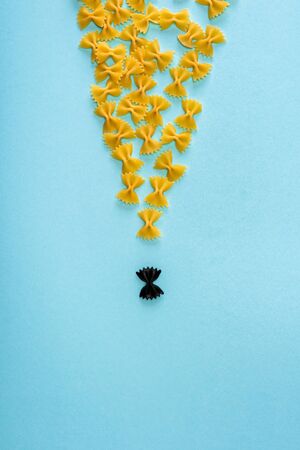 Top view of unique black pasta among yellow on blue background