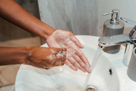 Cropped view of african american woman washing hands with soap in bathroomの写真素材