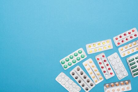 top view of colorful pills in blister packs on blue background