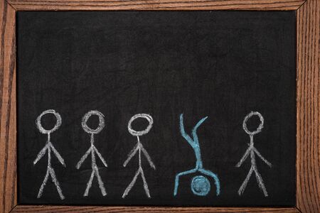 Unique drawn man among another on black board in wooden frameの写真素材