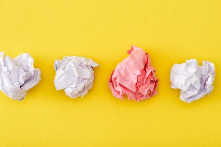 Top view of unique crumpled pink paper among white on yellow backgroundの写真素材