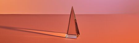 crystal transparent pyramid with light reflection on orange background, horizontal cropの写真素材
