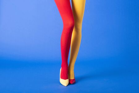 cropped view of model in yellow and red tights and shoes standing on blueの写真素材