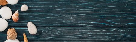 Panoramic shot of top view of pebbles and seashells on dark wooden surface