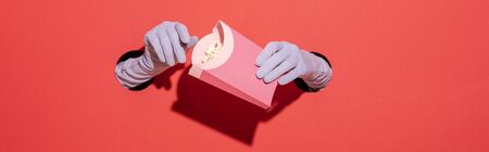 panoramic shot of woman in gloves holding popcorn bucket on redの写真素材