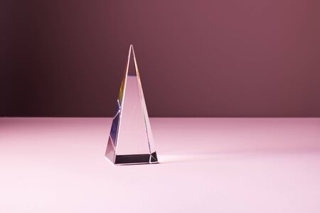crystal transparent pyramid with light reflection on pink backgroundの写真素材