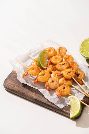 prawns on skewers with lime on parchment paper on wooden board on white backgroundの写真素材