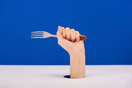 cropped view of woman holding fork isolated on blueの写真素材