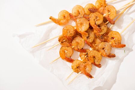 top view of prawns on skewers on parchment paper on white backgroundの写真素材