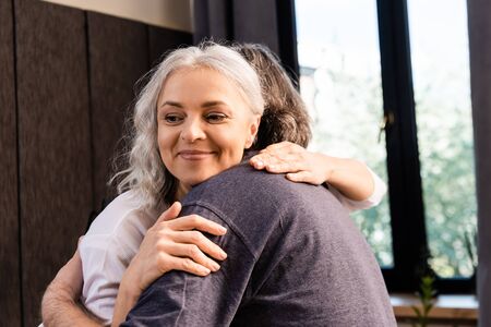 happy middle aged woman hugging with husband at homeの写真素材
