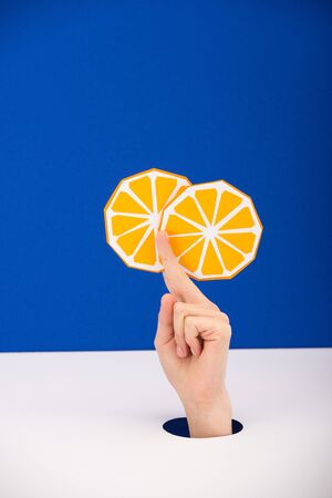 cropped view of woman holding paper orange isolated on blueの写真素材