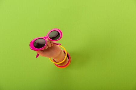 cropped view of woman holding pink sunglasses on greenの写真素材