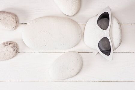 Top view of sea stones with sunglasses on white wooden surfaceの写真素材