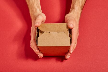 top view of man holding carton takeaway box on redの写真素材