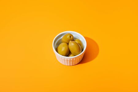 olives in bowl on orange colorful backgroundの写真素材