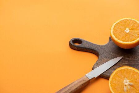 fresh juicy orange halves on cutting board with knife on colorful backgroundの写真素材