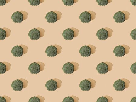 top view of fresh green broccoli on beige background, seamless patternの写真素材