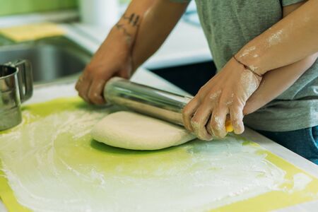 cropped view of mother and toddler son holding rolling pin near raw doughの写真素材