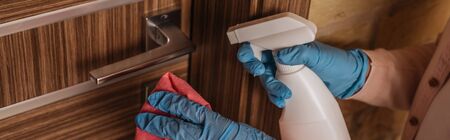 Cropped view of kid in latex gloves holding rag and detergent near door handle, panoramic cropの写真素材