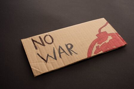 cardboard placard with no war lettering and bomb on black background