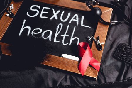 chalkboard with sexual health lettering and sex toys and red ribbon on black silkの写真素材