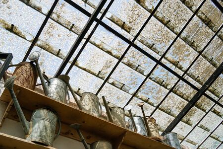 low angle view of rusty watering cans on shelvesの写真素材