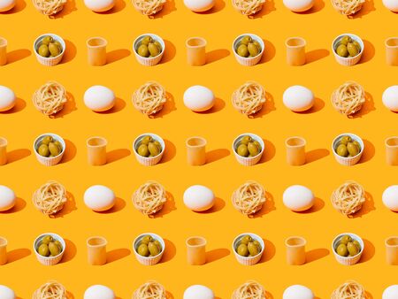 fresh white chicken eggs, pasta and olives on orange colorful background, seamless patternの写真素材