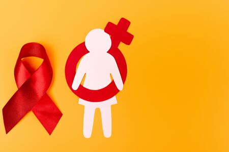 top view of paper person with male gender symbol near red ribbon on orange