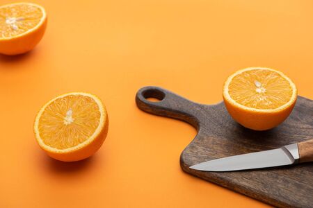 fresh juicy cut oranges on cutting board with knife on colorful backgroundの写真素材