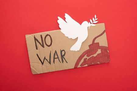 top view of cardboard placard with no war lettering and bomb with white paper dove on red backgroundの写真素材