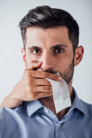 Male hand holding package with cocaine while covering mouth to man isolated on greyの写真素材