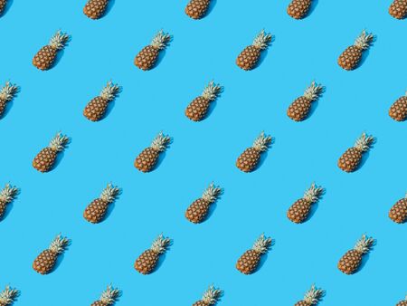 top view of whole ripe pineapples on blue colorful background, seamless patternの写真素材