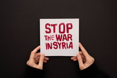 cropped view of woman holding white placard with red stop war in Syria lettering on black backgroundの写真素材