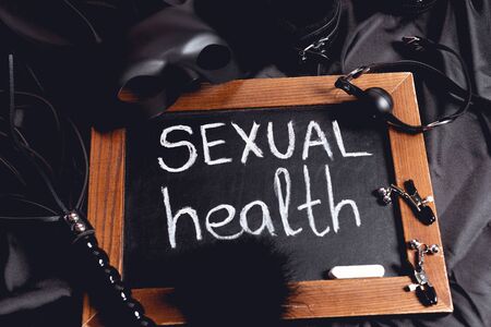 rabbit mask near chalkboard with sexual health lettering and sex toys on black silkの写真素材