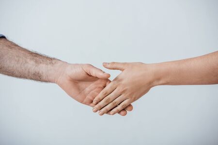 Cropped view of man and woman handshaking isolated on greyの写真素材