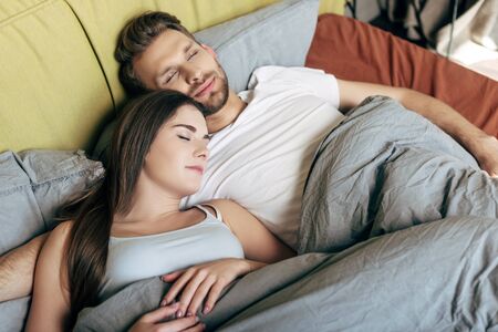 happy man and attractive woman sleeping in bed