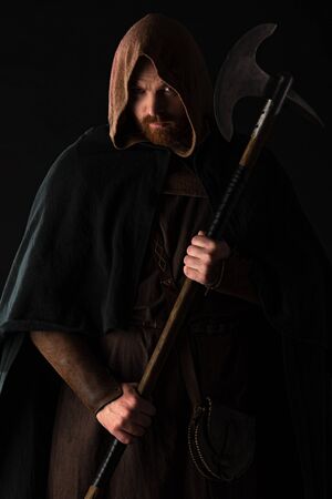 frowning medieval Scottish warrior with battle axe in mantel isolated on black