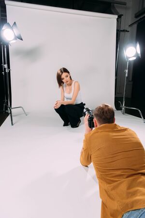 Attractive model posing while working with photographer in photo studioの写真素材